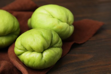 Photo of Fresh green chayote on wooden table, closeup