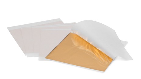 Photo of Many edible gold leaf sheets on white background