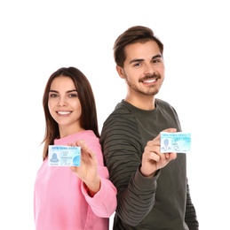 Happy young people with driving licenses on white background