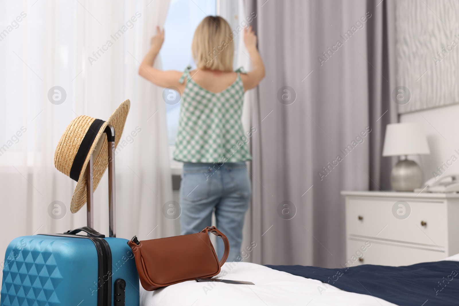 Photo of Guest opening curtains in stylish hotel room, selective focus