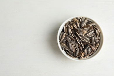 Organic sunflower seeds on white wooden table, top view. Space for text