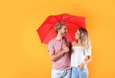 Photo of Couple with red umbrella on color background