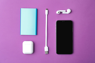 Photo of USB charge cable and gadgets on purple background, flat lay