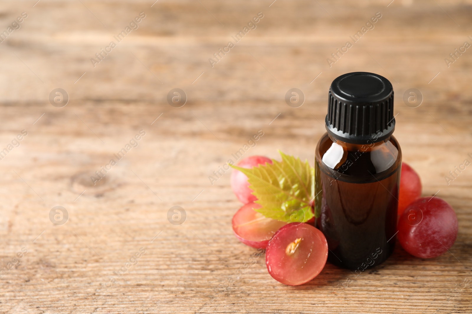 Photo of Bottle with natural grape seed oil on wooden table, space for text. Organic cosmetic