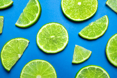 Photo of Juicy fresh lime slices on blue background, flat lay