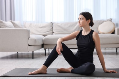 Photo of Beautiful girl sitting on yoga mat at home