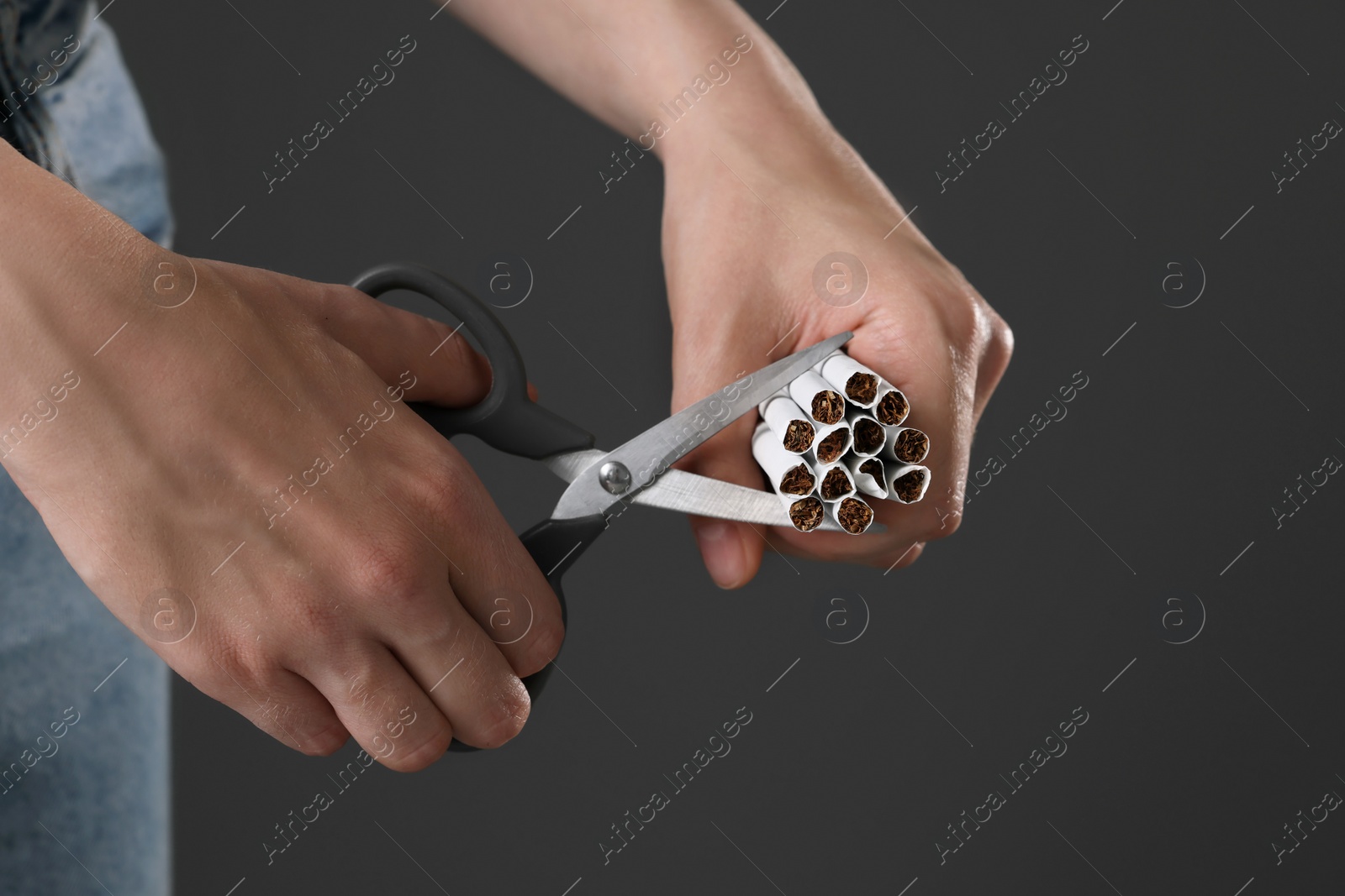 Photo of Stop smoking concept. Woman cutting cigarettes on gray background, closeup