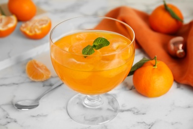Photo of Delicious tangerine jelly on white marble table, closeup