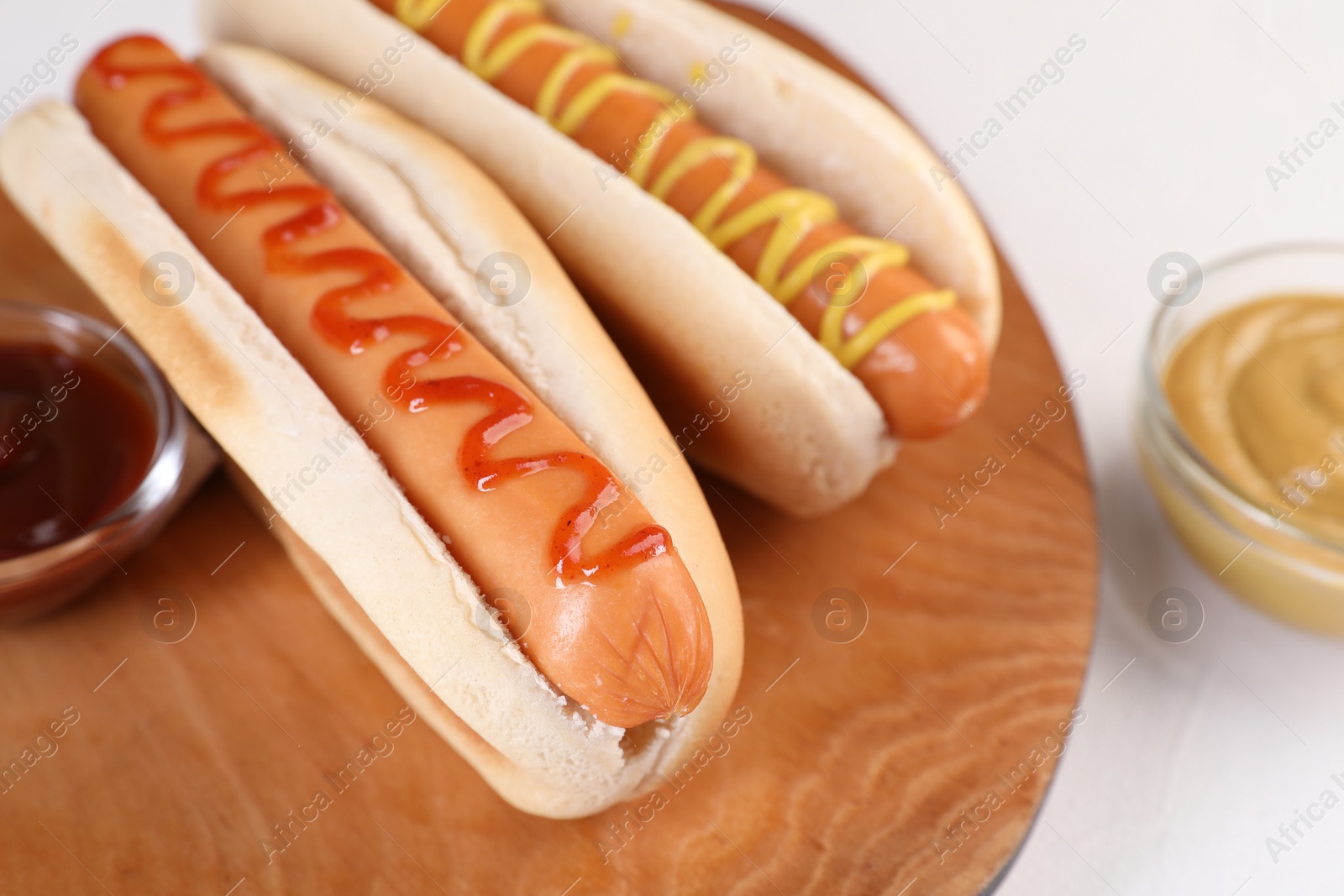 Photo of Tasty hot dogs with ketchup and mustard on white table, closeup