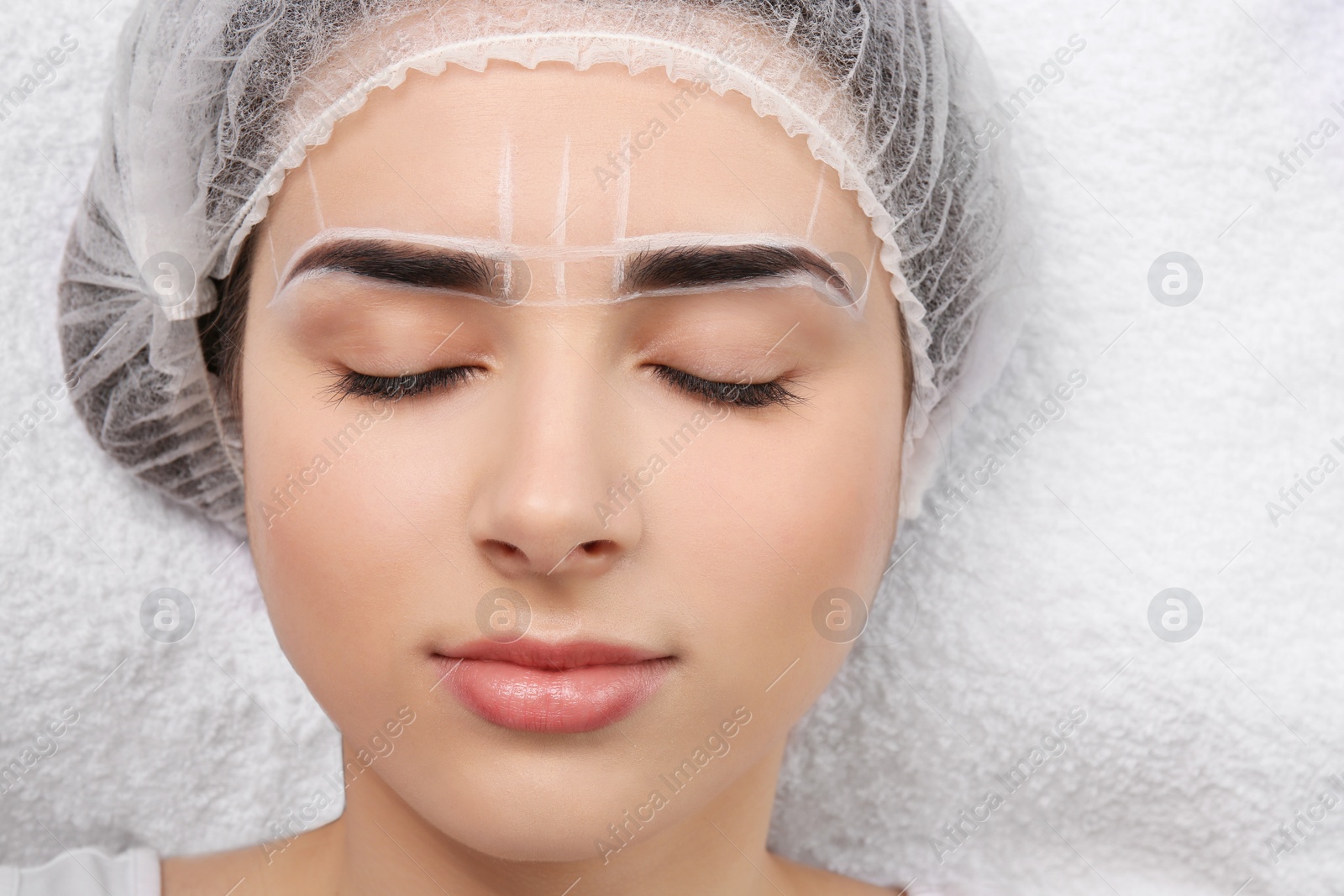 Photo of Young woman with marks on face before eyebrow permanent makeup procedure, closeup