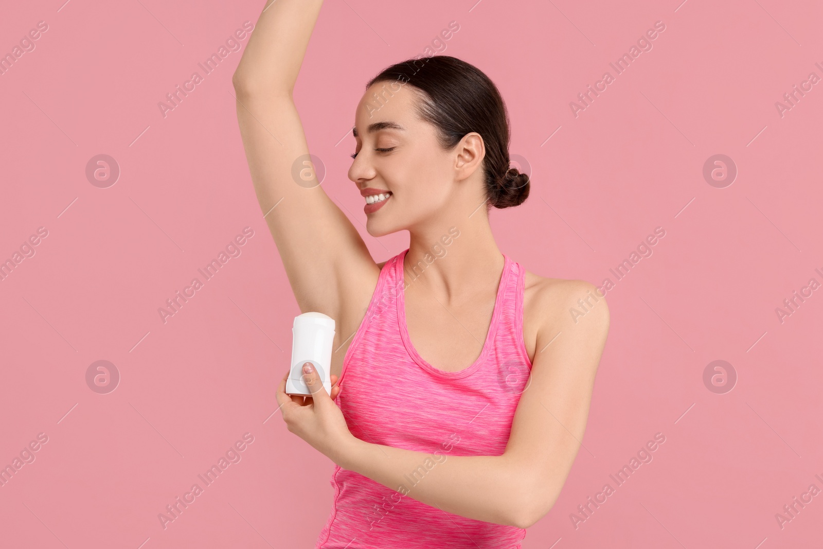 Photo of Beautiful woman applying deodorant on pink background