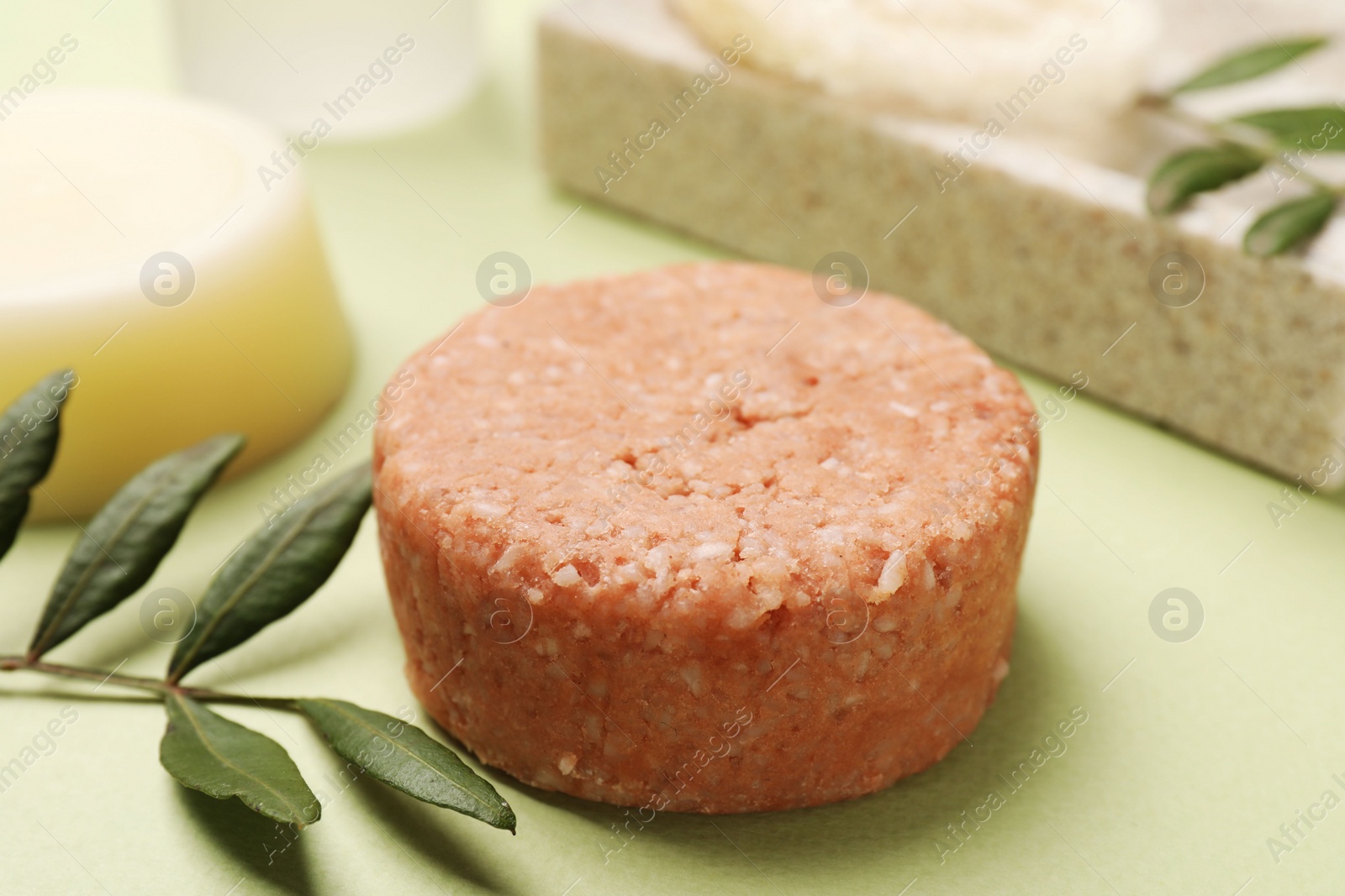 Photo of Solid shampoo bar and leaf on green background, closeup. Hair care