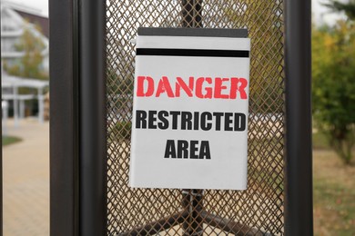 Sign with text Danger Restricted Area on fence outdoors