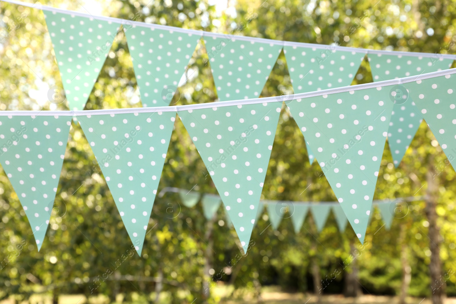 Photo of Light blue bunting flags in park. Party decor