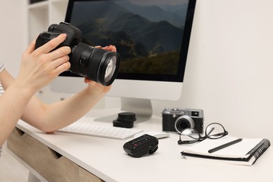 Photographer with camera at white table indoors, closeup