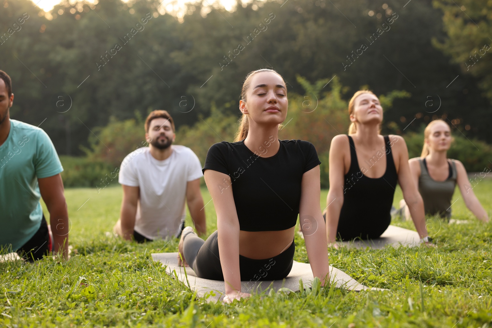 Photo of Group of people practicing yoga on mats outdoors