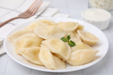 Photo of Plate of delicious dumplings (varenyky) with cottage cheese on white table, closeup