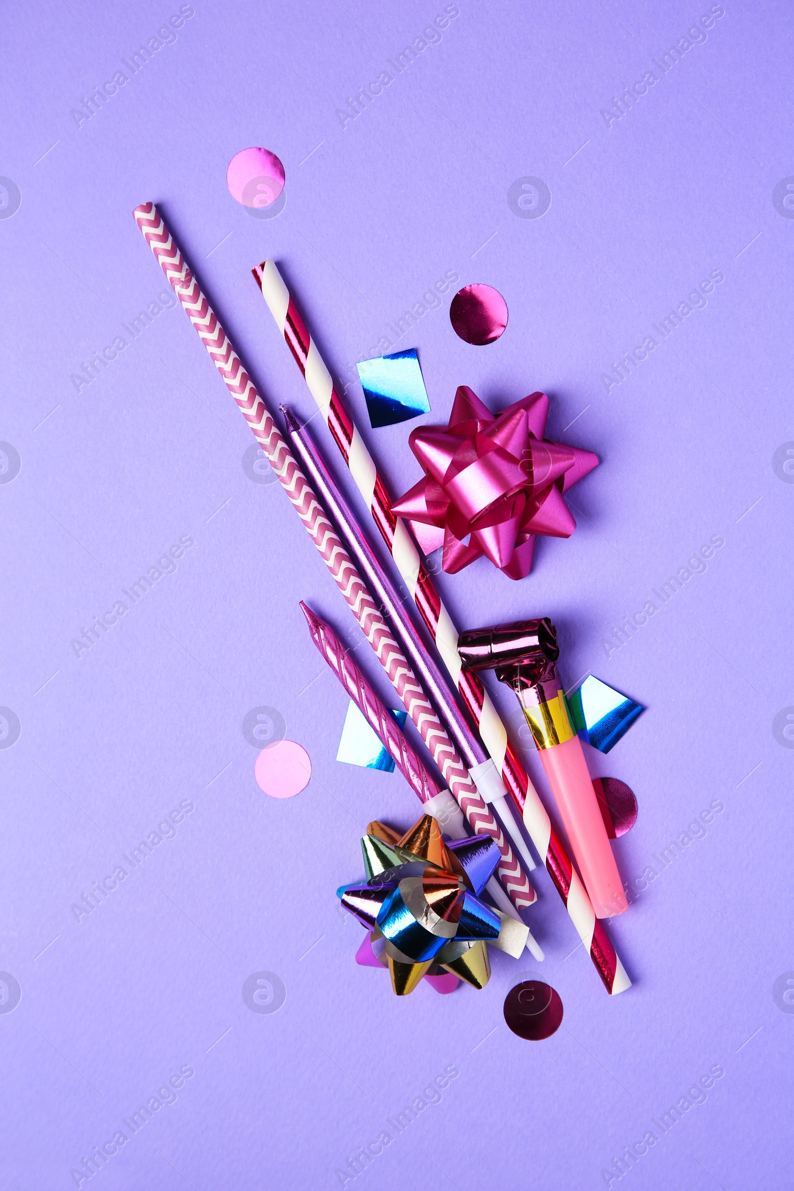 Photo of Party blower, colorful confetti and other festive decor on violet background, flat lay
