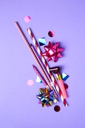 Party blower, colorful confetti and other festive decor on violet background, flat lay