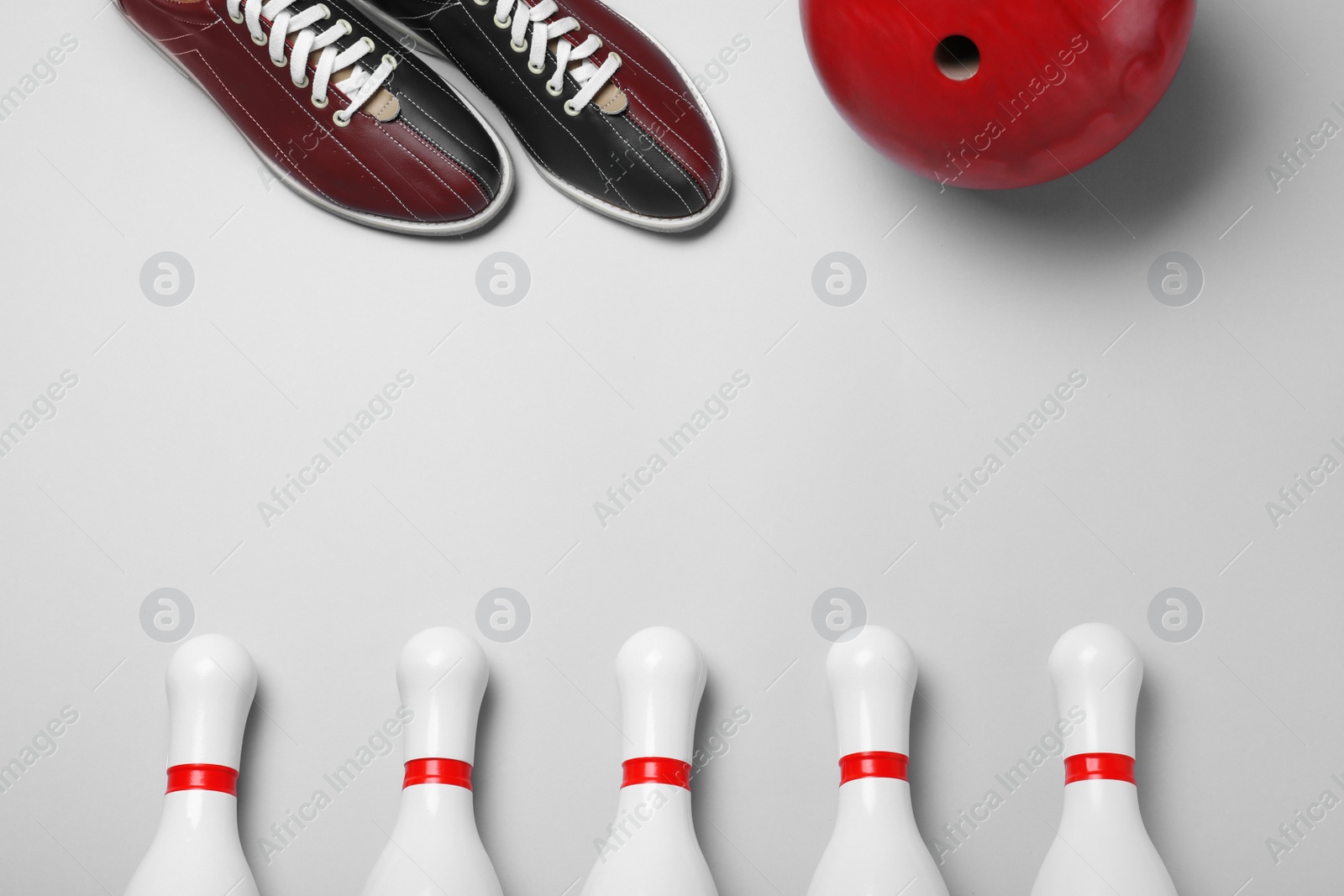 Photo of Bowling ball, shoes and pins on white background, flat lay