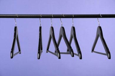 Photo of Black clothes hangers on rack against purple background