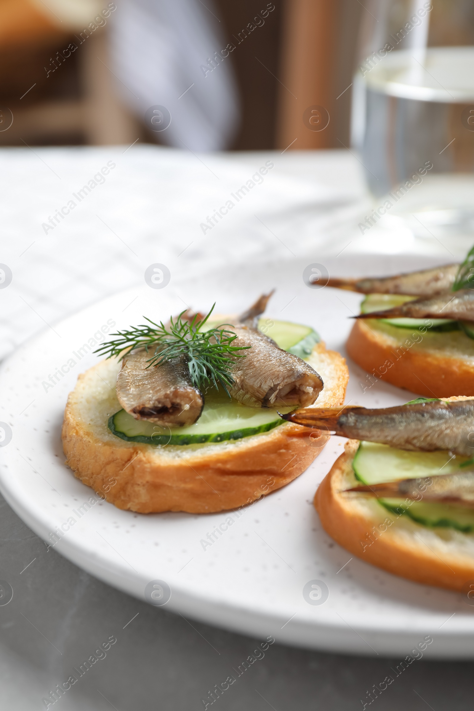 Photo of Delicious sandwiches with sprats, cucumbers and dill on light table