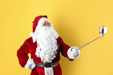 Authentic Santa Claus taking selfie on yellow background