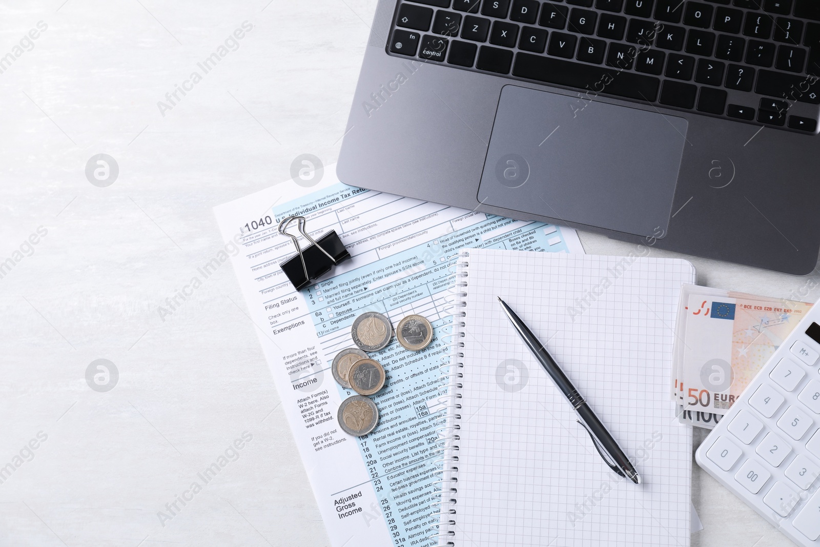 Photo of Tax accounting. Stationery, money, document, laptop and calculator on light grey table, flat lay. Space for text