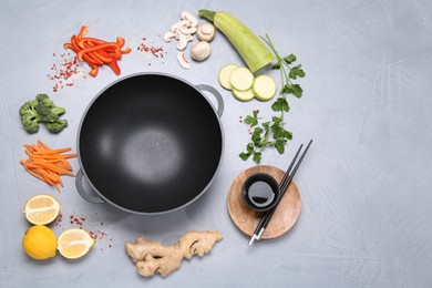 Photo of Wok, chopsticks and different products on grey table, flat lay. Space for text