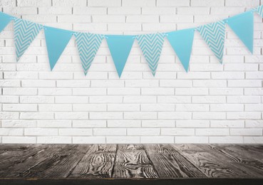 Image of Empty wooden table and decorative bunting flags hanging on brick wall