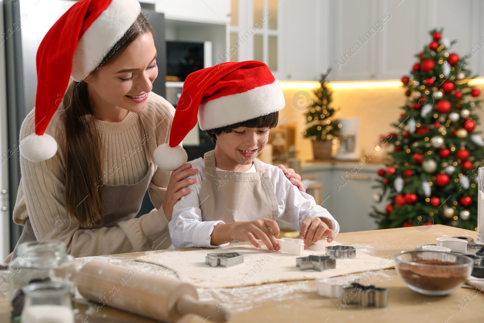 Photo of Mother with her cute little son making Christmas cookies in kitchen