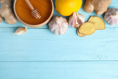 Photo of Fresh garlic and other natural cold remedies on light blue wooden table, flat lay. Space for text