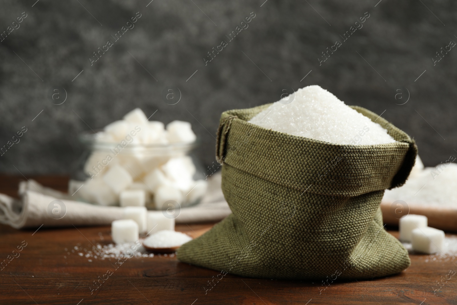 Photo of Granulated sugar in sack on wooden table. Space for text