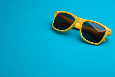 Photo of Stylish sunglasses on blue background, space for text. Fashionable accessory