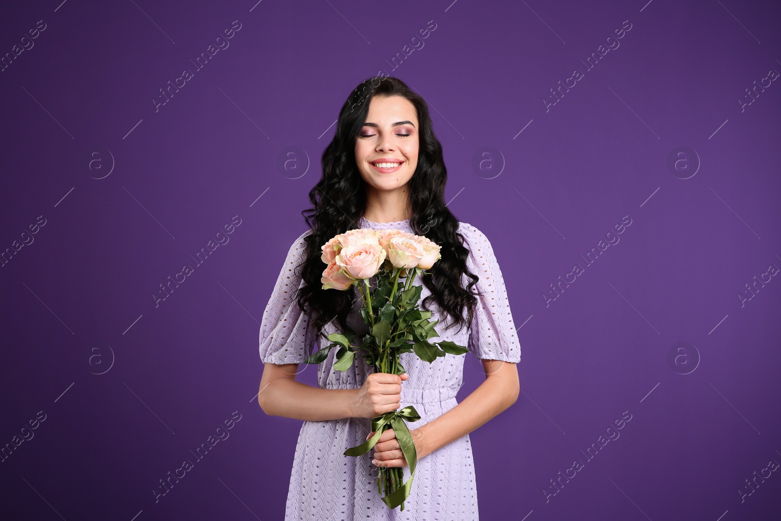 Photo of Portrait of smiling woman with beautiful bouquet on purple background