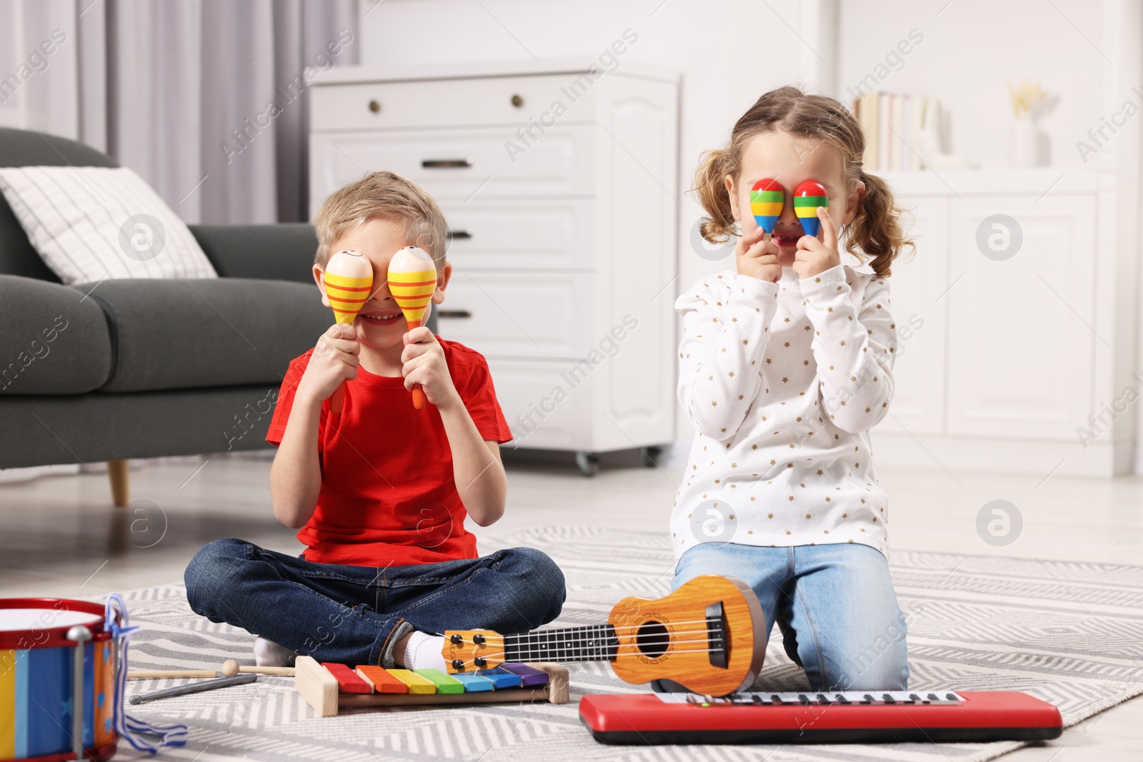 Photo of Little children playing toy musical instruments at home