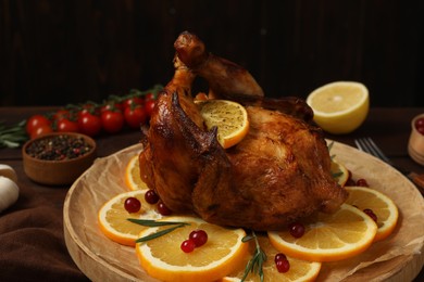 Photo of Baked chicken with orange slices on wooden board