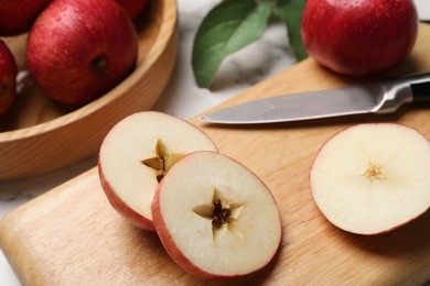 Photo of Cut red apple and knife on white table, closeup