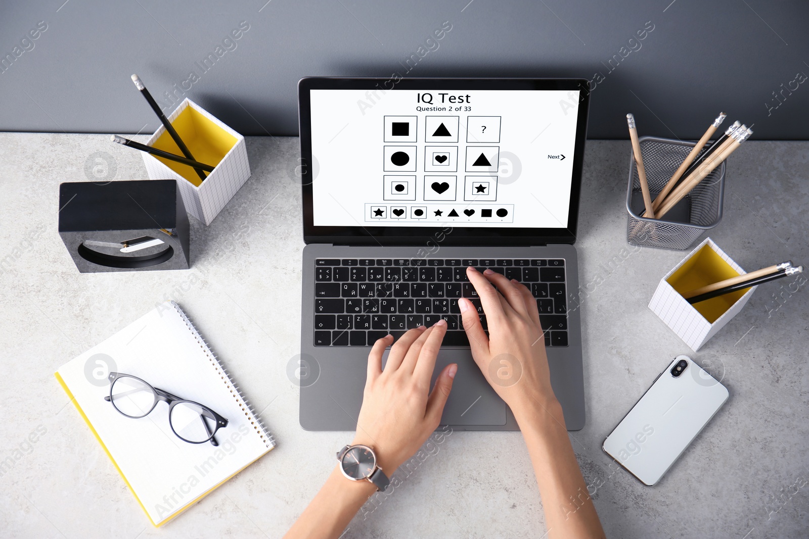 Image of Woman using laptop for taking IQ test at grey table, top view