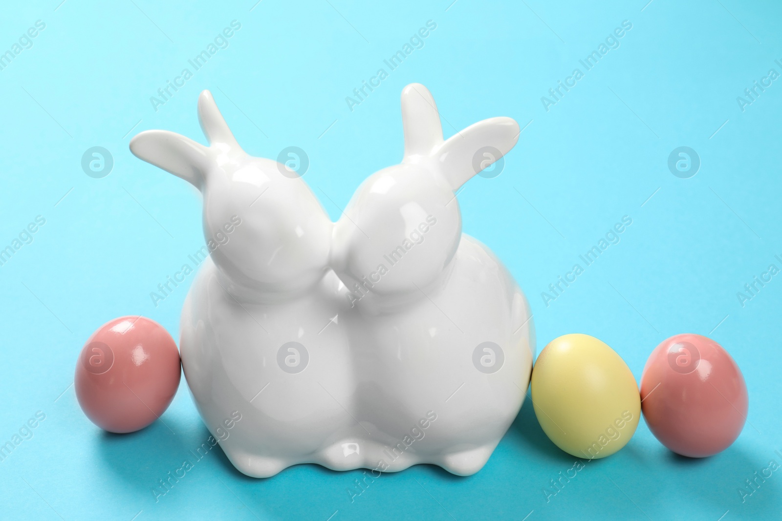 Photo of Ceramic Easter bunnies and dyed eggs on color background