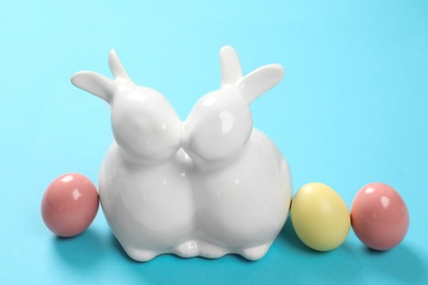 Photo of Ceramic Easter bunnies and dyed eggs on color background