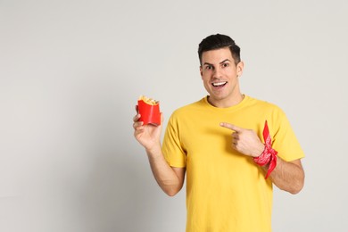 Man with French fries on grey background, space for text