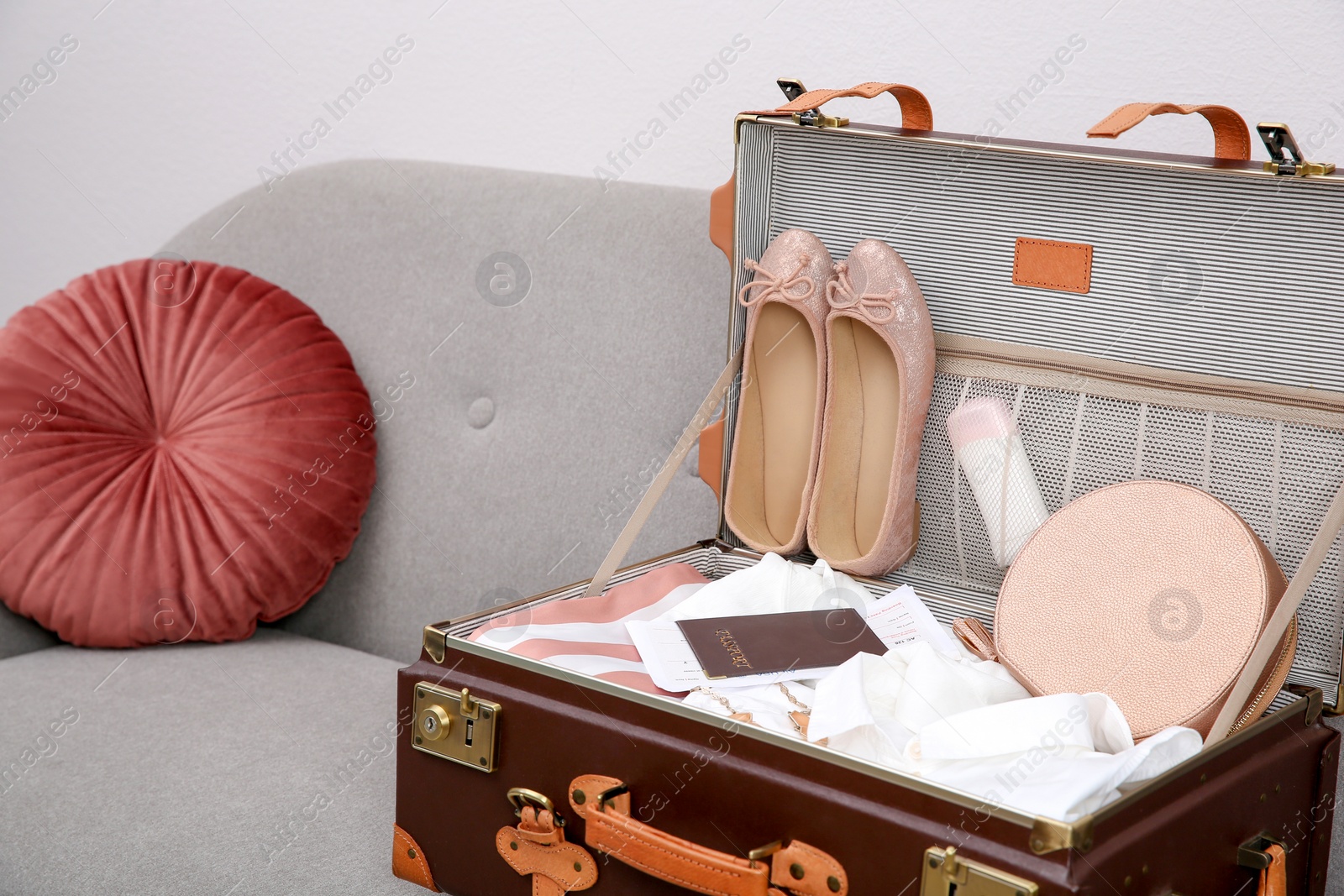 Photo of Vintage suitcase with clothes and shoes on sofa indoors
