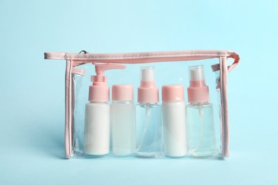 Photo of Cosmetic travel kit in plastic bag on light blue background