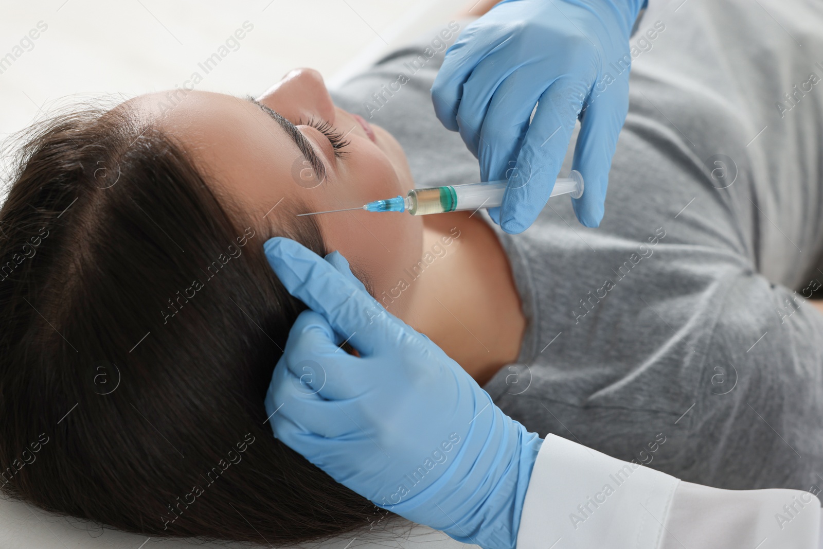 Photo of Trichologist giving injection to patient, closeup view
