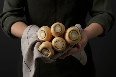 Photo of Woman holding fresh ripe parsnips on black background, closeup