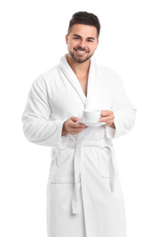 Handsome man in bathrobe with cup of coffee on white background