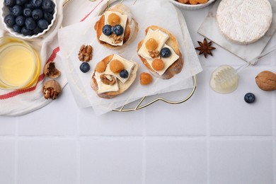 Tasty brie cheese sandwiches on white tiled table, flat lay. Space for text