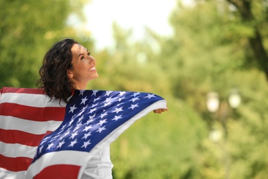 Photo of Happy young woman with American flag in park on sunny day