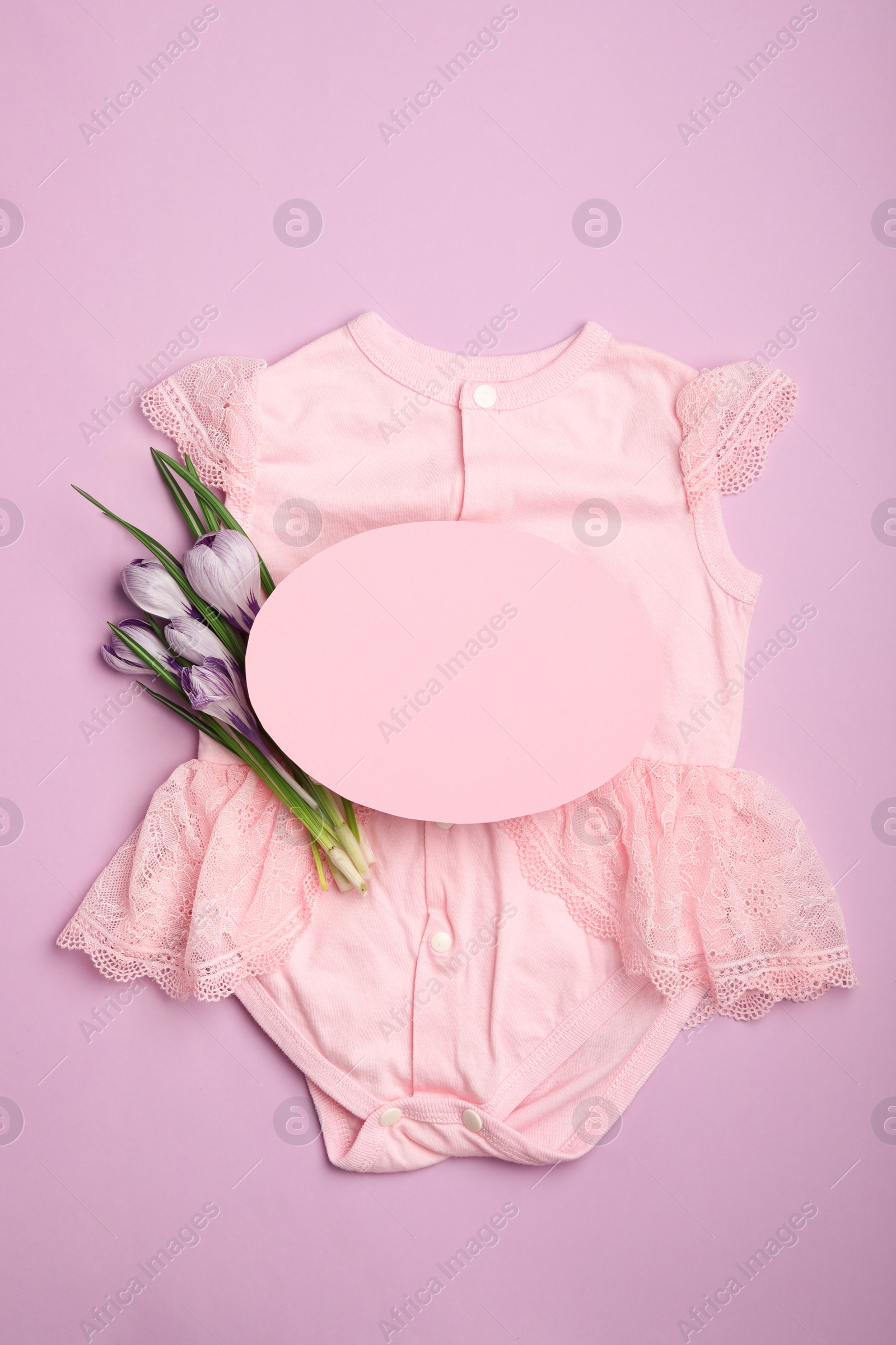 Photo of Child's clothes, flowers and card with space for text on pink background, top view